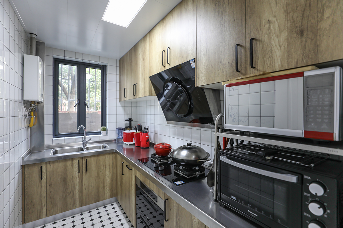 厨房橱柜颜色选择原木色，和客餐厅整体呼应。在瓷砖的选择上选择了黑白格子砖，相信喜欢北欧风格的人都喜欢它。橱柜天面选用不锈钢台面，方便日后打理。
